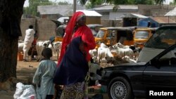 Seorang perempuan membawa 2 anaknya di jalanan antara Jos-Maiduguri, di mana militer Nigeria mengumumkan diberlakukannya jam malam (19/5).