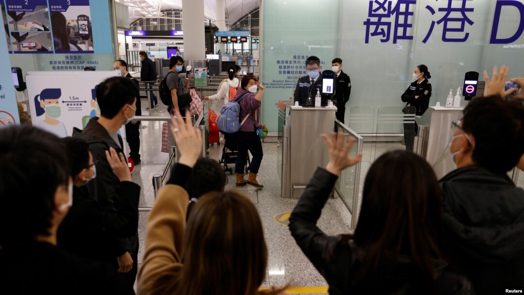 FILE - Members of a family, who are emigrating to Scotland, wave good-bye to their friends who are seeing them off before their departure at Hong Kong International Airport in Hong Kong, Dec. 17, 2020. 
