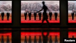 A pedestrian walks past electronic signs displaying pictures of China's Politburo Standing Committee members at a subway station, Shanghai, June 18, 2013.