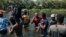 FILE - Migrants wade through the Rio Grande as they move from Ciudad Acuña, Mexico, into Del Rio, Texas, Sept. 19, 2021. 