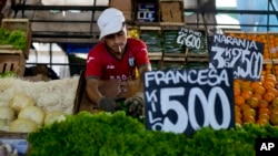 A vendor arranges vegetables at a market on the outskirts of Buenos Aires, Argentina, Wednesday, Jan. 10, 2024. The price for lettuce reads 500 Argentine pesos per kilogram, or about .60 US cents. (AP Photo/Natacha Pisarenko)