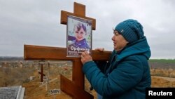Ірина Орфіняк біля могили її онучки Вероніки, яка загинула разом із батьком під час обстрілів Росією Маріуполя, 9 листопада 2022. REUTERS/Alexander Ermochenko