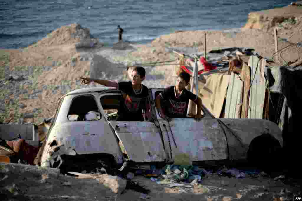 Anak-anak Palestini bermain di puing-puing sebuah mobil tua di kamp pengungsi Shati di Gaza City.