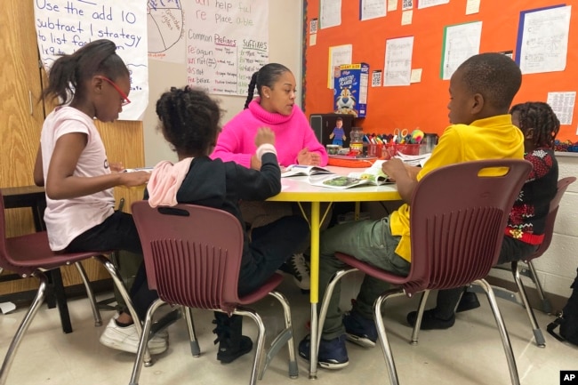 Third-grade teaching assistant Keione Vance leads a reading session with a small group of students at Boyd Elementary School in Atlanta, Dec. 15, 2022. (AP Photo/Sharon Johnson)