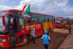 An adviser on repatriation hangs a Burundian flag on the lead bus transporting refugees arriving at the Gisuru border in Ruyigi, Burundi, Oct. 3, 2019.