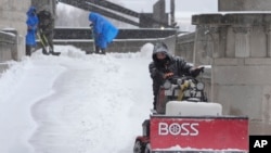 Workers clear snow from a walkway in St. Louis, Missouri, Jan. 5, 2025.