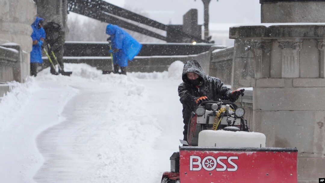 Workers clear snow from a walkway in St. Louis, Missouri, Jan. 5, 2025.