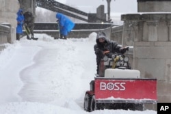 Los trabajadores limpian la nieve de una pasarela el domingo 5 de enero de 2025 en St. Louis. (Foto AP/Jeff Roberson)