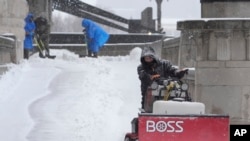 Workers clear snow from a walkway in St. Louis, Missouri, Jan. 5, 2025.