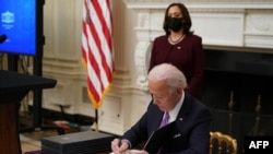 Perezida Joe Biden asinya amategeko ya perezida ku musi wiwe wa mbere ku butegetsi, kw'italiki 21/01/2021.