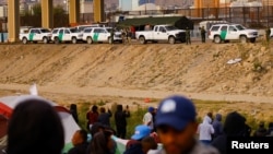 Agentes de la Patrulla Fronteriza de EEUU se paran frente a migrantes venezolanos en un campamento a orillas del Río Grande, visto desde Ciudad Juárez, México, el 15 de noviembre de 2022. 