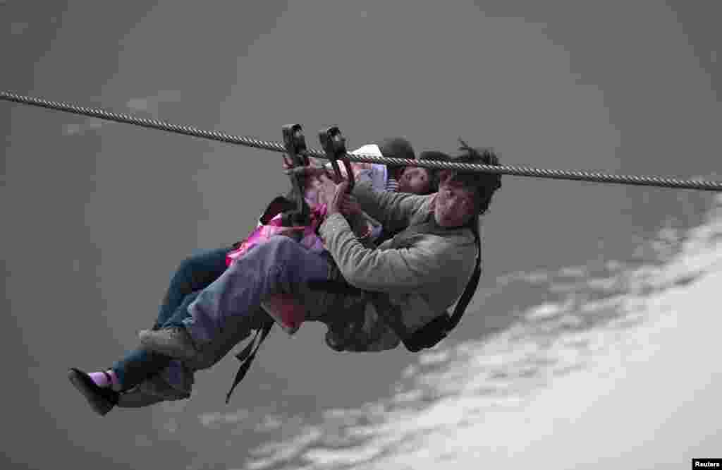 A man, his wife and their child use a zip-line to cross the Nujiang River in Lazimi village of Nujiang Lisu Autonomous Prefecture, China. Residents have been using the zip-line for years to cross the river as there is no bridge nearby, local media reported.