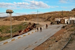 FILE - Iraqi army soldiers walk down the road leading to the Sayida Zeinab shrine in Sinjar, Iraq, Dec. 4, 2020.