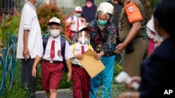 Siswa yang memakai masker tiba di hari pertama sekolah dibuka kembali di sebuah sekolah dasar di Jakarta, Senin, 30 Agustus 2021. (Foto: AP)