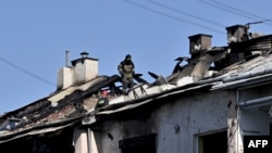 A rescuer examines a roof of a damaged residential building after missile strike on the city of Lviv, western Ukraine on Aug.15, 2023.