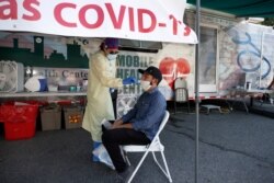 Nurse Tanya Markos administers a coronavirus test on patient Ricardo Sojuel at a mobile COVID-19 testing unit in Lawrence, Mass., July 2, 2020.