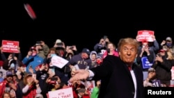 FILE - U.S. President Donald Trump throws a face masks into the crowd as he arrives to hold a campaign rally at John Murtha Johnstown-Cambria County Airport in Johnstown, Pennsylvania, Oct. 13, 2020. 