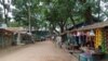 FILE - People walk along the shops in the Kutupalong Rohingya refugee camp area where authorities imposed lockdown to contain the spread of the Covid-19 coronavirus in Ukhia, Bangladesh, May 21, 2021.