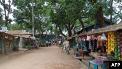 FILE - People walk along the shops in the Kutupalong Rohingya refugee camp area where authorities imposed lockdown to contain the spread of the Covid-19 coronavirus in Ukhia, Bangladesh, May 21, 2021.