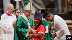 Indigenous peoples, some with their faces painted and wearing feathered headdresses, stand by Pope Francis as he celebrates an opening Mass for the Amazon synod, in St. Peter's Basilica, at the Vatican, Oct. 6, 2019. 