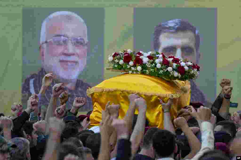 Hezbollah members carry the coffins of Hezbollah commanders Ibrahim Kobeisi, seen in the picture left, and Hussein Ezzedine, right, during their funeral procession in Beirut&#39;s southern suburb.