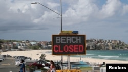 在澳大利亚悉尼，人们走过邦迪海滩的“海滩关闭”标志，因为海滩仍然关闭，以防止冠状病毒病(COVID-19)的传播。(2020年4月1日)