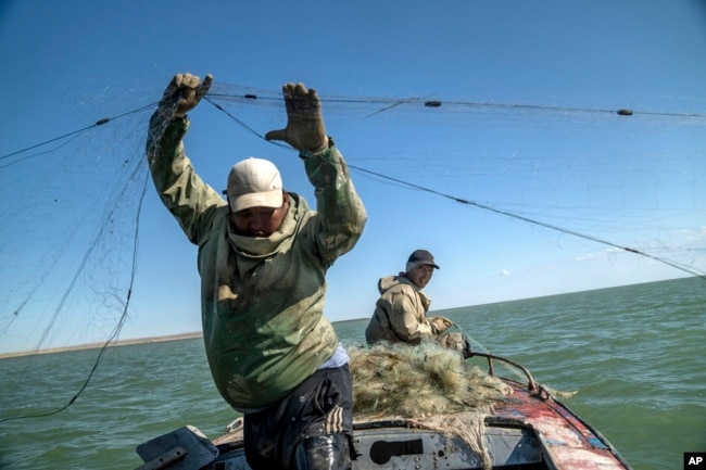 Serzhan Seitbenbetov, left, and Omirserik Ibragimov fish in a part of the Aral Sea with water, far away from their village Tastubek, outside Aralsk, Kazakhstan, Sunday, July 1, 2023. (AP Photo/Ebrahim Noroozi)