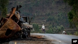 FILE - A man crosses near a destroyed truck on a road leading to the town of Abi Adi, in the Tigray region of northern Ethiopia, May 11, 2021. 