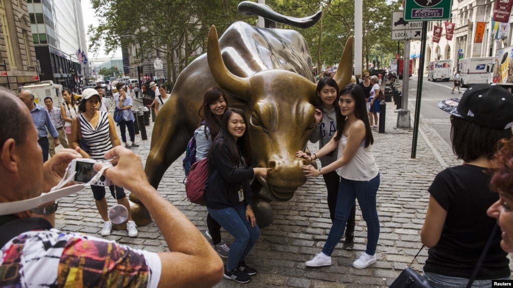 资料照：中国游客在纽约华尔街的铜牛前合影。（2015年8月24日）