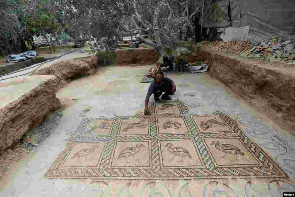 Palestinian farmer Salman al-Nabahin cleans a mosaic floor he discovered at his farm and which dates back to the Byzantine era, according to officials, in the central Gaza Strip.