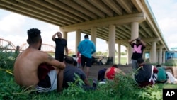 FILE - Migrants wait to be processed by the Border Patrol after illegally crossing the Rio Grande river from Mexico into the U.S. at Eagle Pass, Texas, Aug. 26, 2022. 