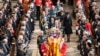 Raja Charles III dan anggota keluarga kerajaan Inggris mengikuti di belakang peti mati Ratu Elizabeth II, yang terbungkus Royal Standard dengan Imperial State Crown dan bola dan tongkat kerajaan, dalam upacara pemakaman kenegaraan di Westminster Abbey, Senin 19 September 2022.