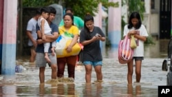 A family evacuates to higher ground as they wade through floodwaters from Typhoon Noru in San Miguel town, Bulacan province, Philippines, Sept. 26, 2022.