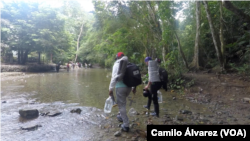 Migrantes venezolanos atraviesan un río, el jueves 15 de septiembre de 2022, en uno de los últimos puntos seguros antes de tomar la peligrosa y espesa selva del Darién que une a Centroamérica con el sur del continente.