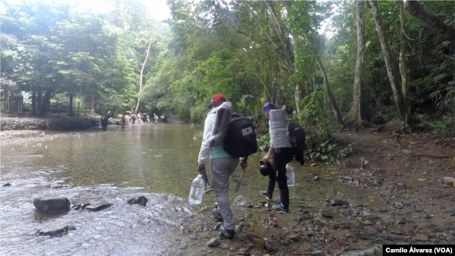 Migrantes venezolanos atraviesan un río, el jueves 15 de septiembre de 2022, en uno de los últimos puntos seguros antes de tomar la peligrosa y espesa selva del Darién que une a Centroamérica con el sur del continente.