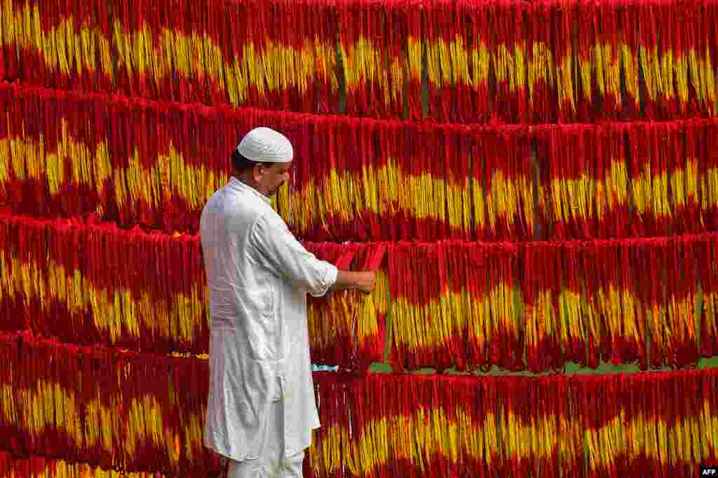 A workshop owner checks freshly-dyed Kalawa threads, a traditional sacred orange-yellow thread used in Hindu rituals, ahead of the Navratri festival at Lalgopalganj village some 45 kms from Allahabad, India.