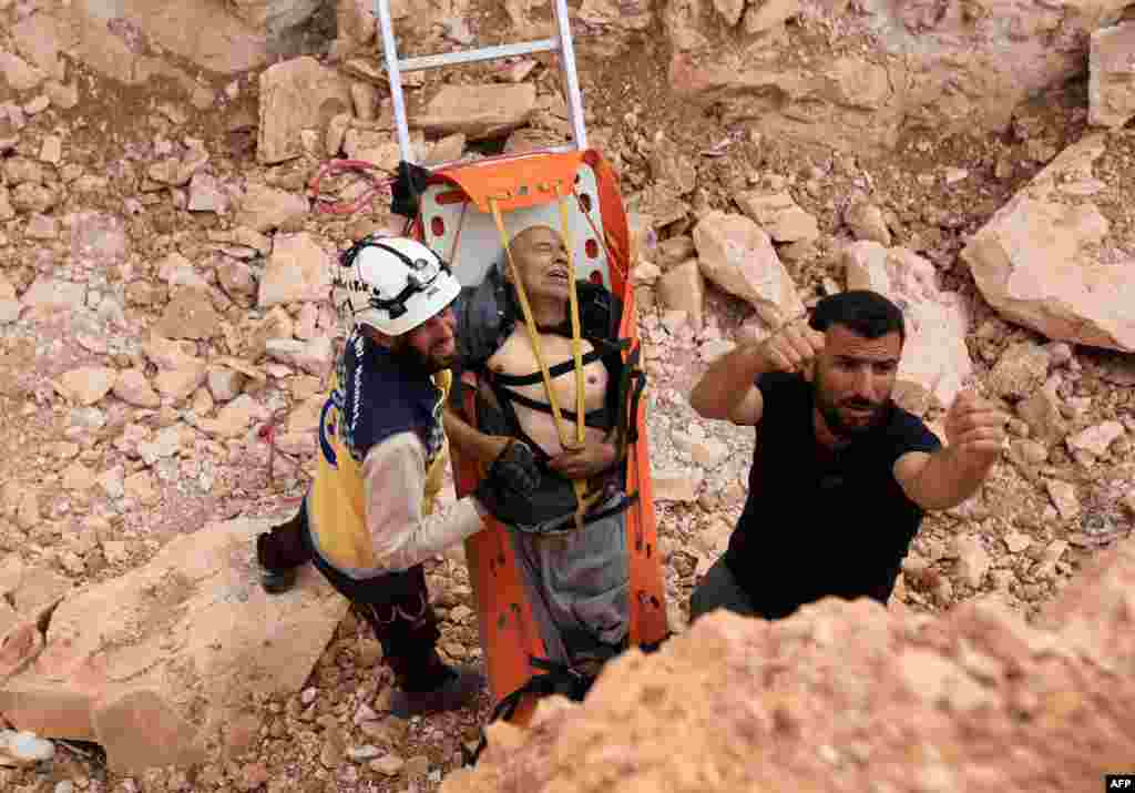 Members of the Syrian civil defense, known as the White Helmets, remove a wounded man from the site after a landmine reportedly exploded under the bus taking them east of the opposition-held city of Al-Bab in the northern Aleppo province.