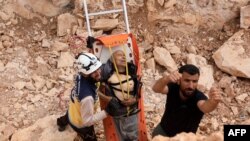 Members of the Syrian civil defense, known as the White Helmets, remove a wounded man from the site after a landmine reportedly exploded under the bus taking them east of the opposition-held city of Al-Bab in the northern Aleppo province.