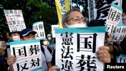 日本部分民众站在街头，手举反对给予日本前首相安倍晋三国葬待遇的标牌。 -路透社资料照