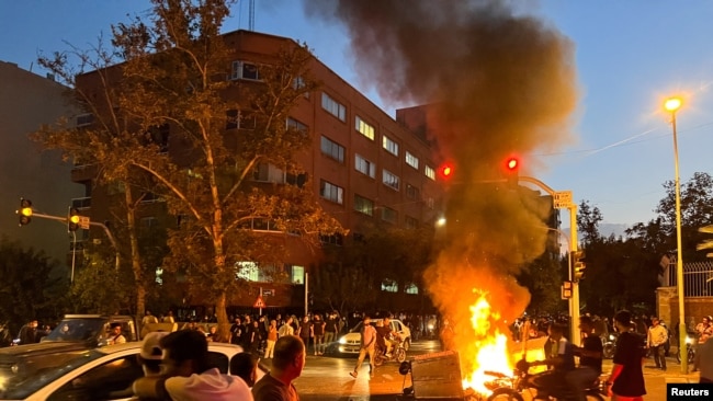 A police motorcycle burns during a protest over the death of Mahsa Amini, a woman who died after being arrested by the Islamic republic's morality police, in Tehran, Iran Sept. 19, 2022. (West Asia News Agency via Reuters)