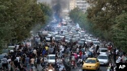 
In this Sept. 21, 2022, photo taken by an individual not employed by the Associated Press and obtained by the AP outside Iran, demonstrators block a street during a protest over the death of a woman who was detained by the country's morality police, in downtown Tehran.