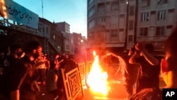 In this Sept. 21, 2022, photo taken by an individual not employed by the Associated Press and obtained by the AP outside Iran, protesters make fire and block the street during a protest over the death of a woman who was detained by the morality police, in