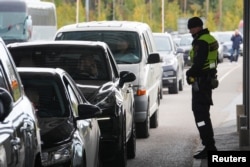 A Finnish border guard officer stands near cars queued to enter Finland from Russia in Vaalimaa, Finland Sept. 23, 2022.