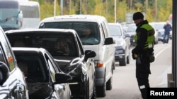 A Finnish border guard officer stands near cars queued to enter Finland from Russia in Vaalimaa, Finland Sept. 23, 2022.