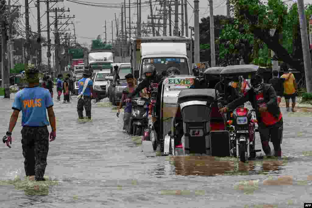 Residents and motorists commute along a flooded highway in the aftermath of the typhoon in San Ildefonso, Bulacan province on Sept. 26, 2022. 