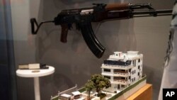 A model of the house where the CIA killed al-Qaida leader Ayman al-Zawahri is displayed below a rifle used by Michael Spann, the first American killed in Afghanistan, in the refurbished museum at the CIA headquarters in Langley, Va., on Sept. 24, 2022. 