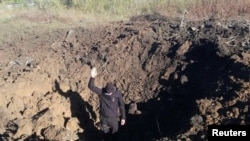 A police officer stands on a bottom of a shell crater left by a Russian military strike at a compound of the Pivdennoukrainsk Nuclear Power Plant, amid Russia's invasion of Ukraine, in Yuzhnoukrainsk, Mykolaiv region, Ukraine, in this handout picture rele