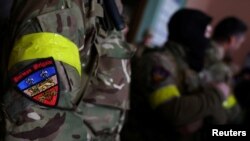 FILE - A badge is pictured on a uniform of a foreign fighter from the U.K. preparing to depart with others for the front line in the east of Ukraine, at the main train station in Lviv, Ukraine, March 5, 2022.