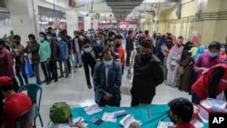 বাংলাদেশের ঢাকায় করোনভাইরাস সংক্রমণের বৃদ্ধির মধ্যে বিপুল সংখ্যক লোক কোভিড-১৯ ভ্যাকসিন গ্রহণের জন্য লাইনে দাঁড়িয়েছে। রবিবার, ৩০ জানুয়ারী, ২০২২। (ফাইল ছবি) 