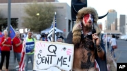 FILE - In this Nov. 5, 2020, file photo, Jacob Anthony Chansley, who also goes by the name Jake Angeli, a QAnon believer, speaks to a crowd of President Donald Trump supporters outside of the Maricopa County Recorder's Office in Phoenix.